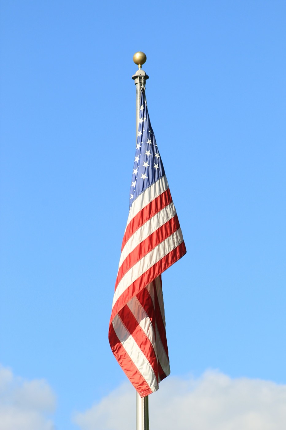 Bandera estadounidense en un asta contra un cielo azul despejado